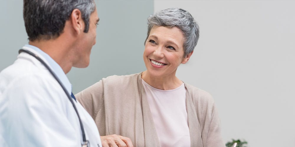 older woman speaking with her doctor about breast implant removal in Bloomfield Township, MI