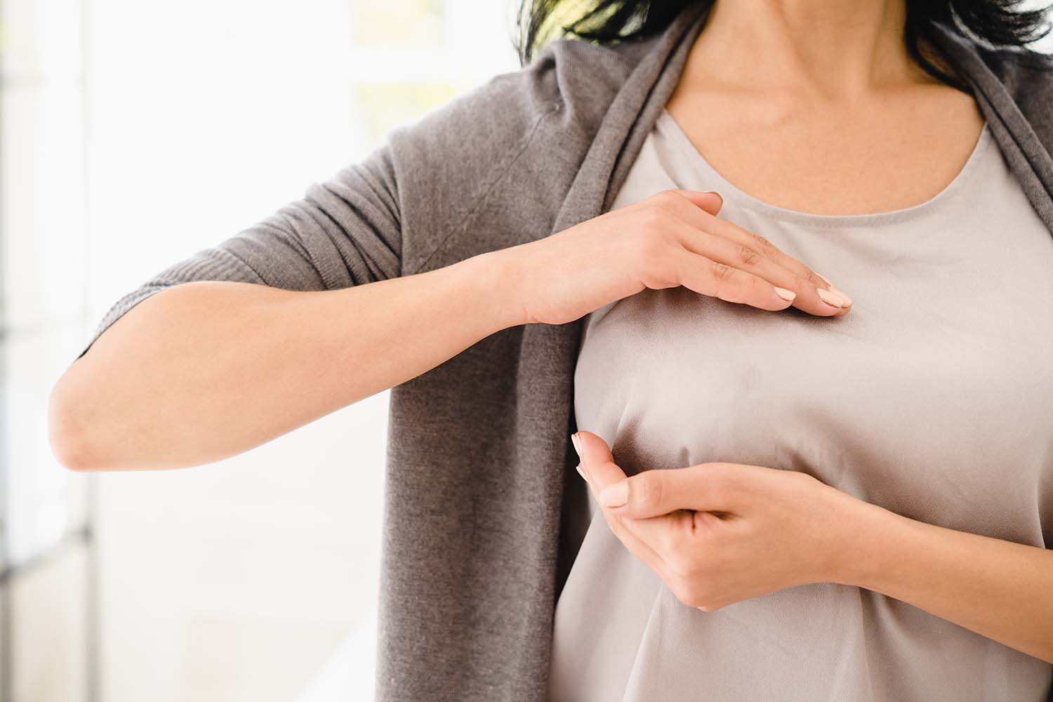 A woman performing a breast self-exam. Many patients use self-checks to detect mold in breast implants, specifically searching for saline breast implant mold symptoms.