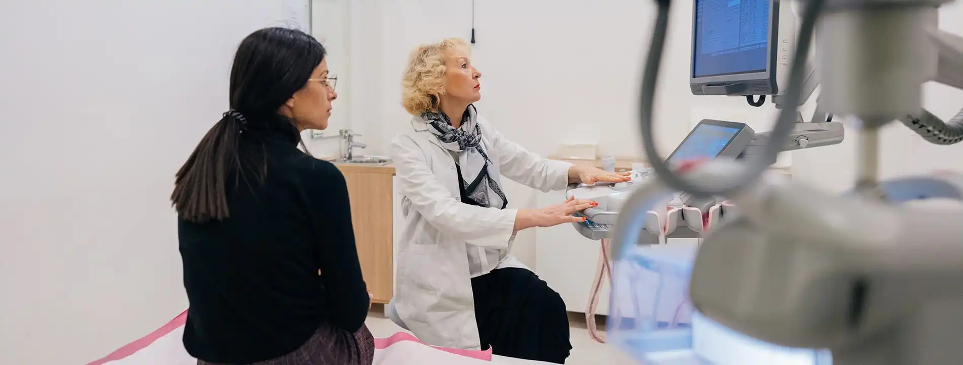 Surgeon in white coat explaining procedure to patient using medical monitor