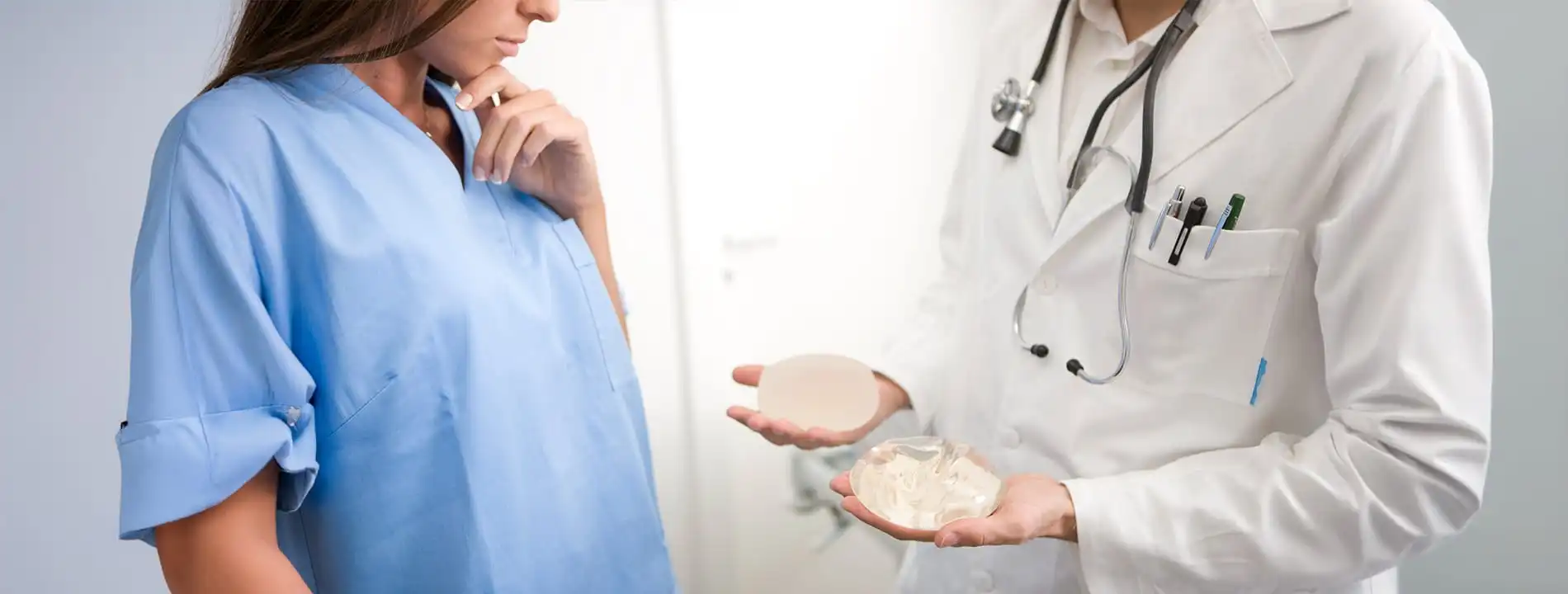 Surgeon showing patient two breast implant options during consultation
