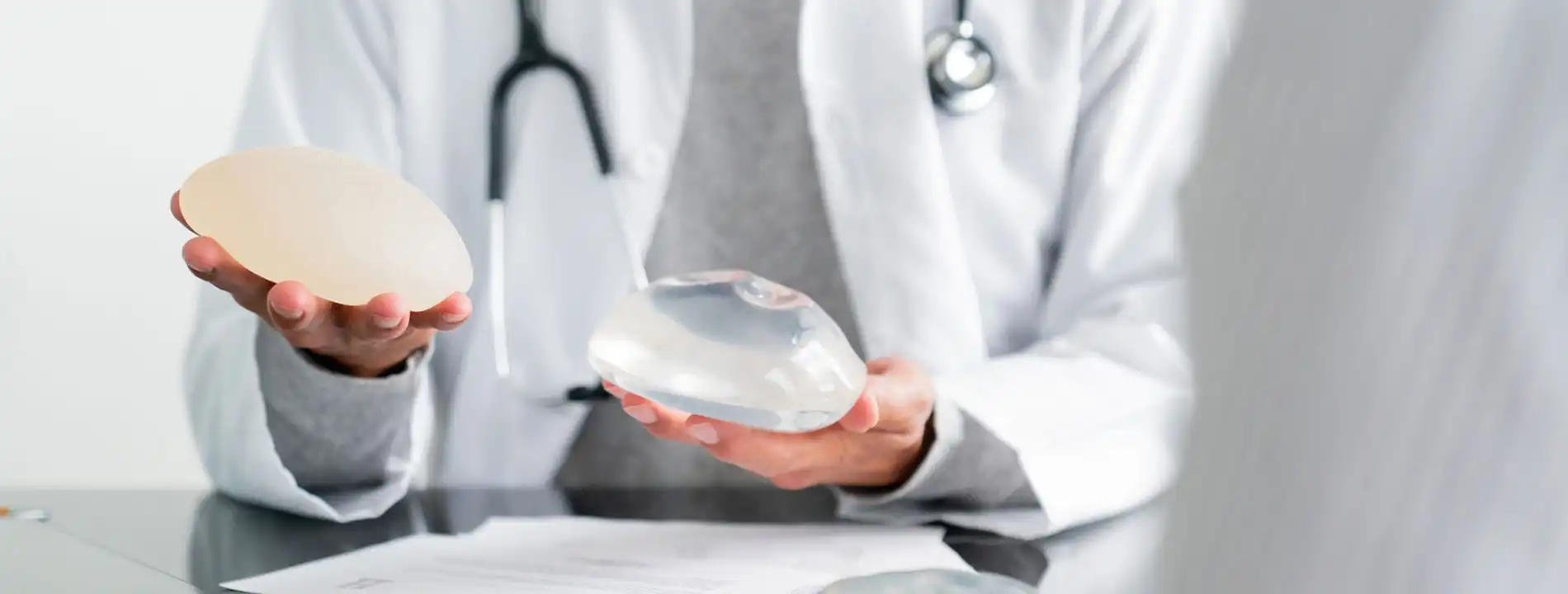 Surgeon holding two different breast implants for patient comparison
