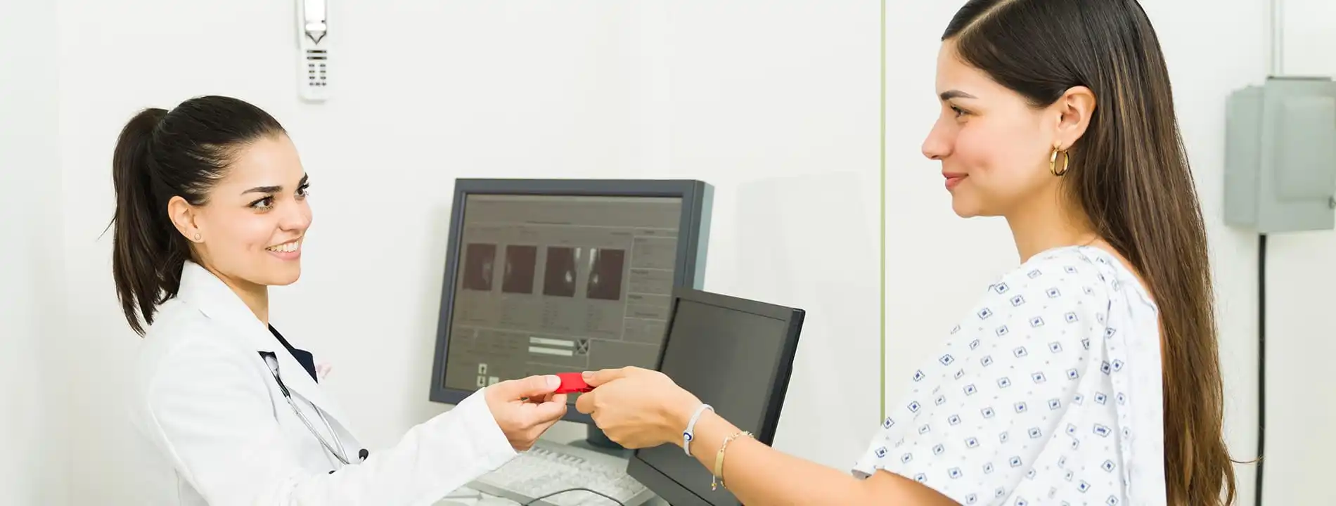 Plastic surgeon showing digital imaging results on monitor to patient in medical consultation room
