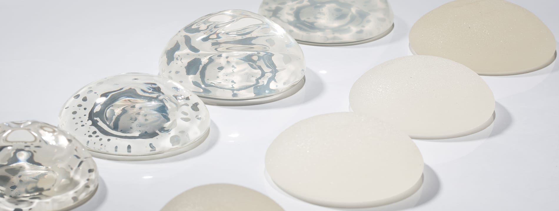 Breast implants in various sizes and styles displayed on white surface