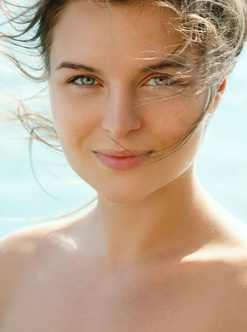 Close-up of woman's face with windswept hair and glowing complexion