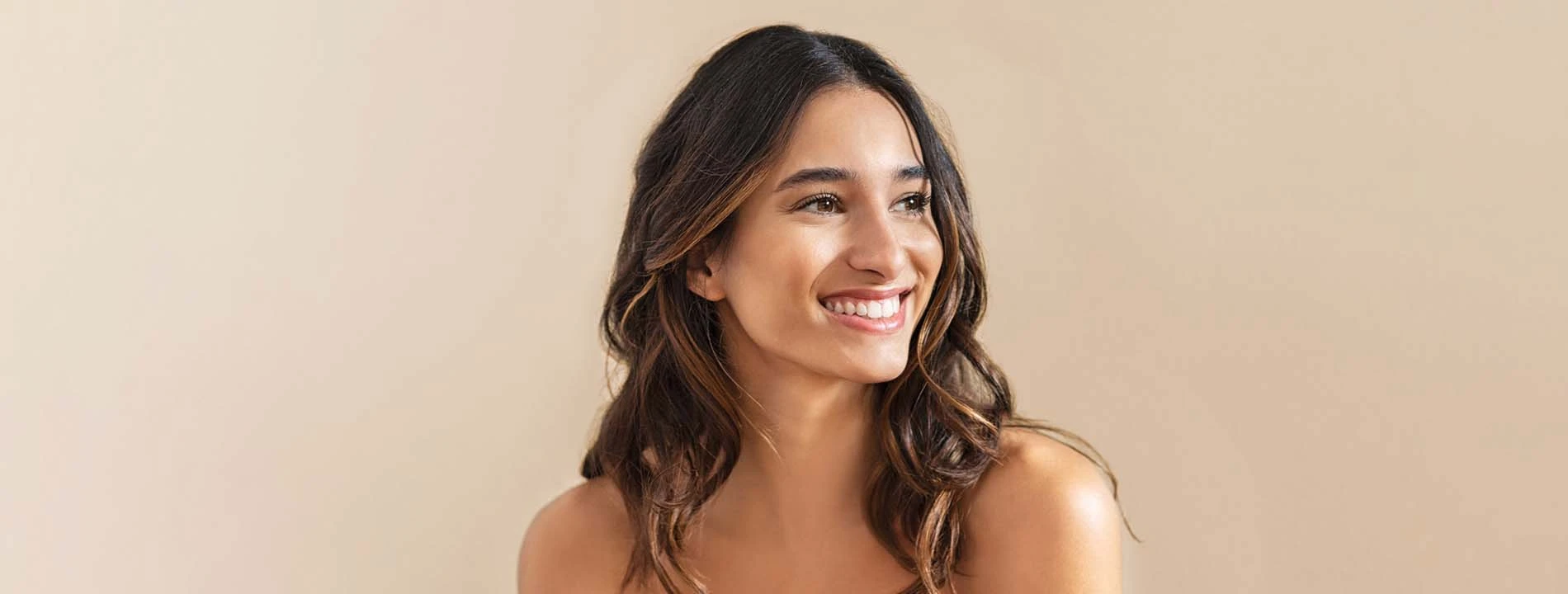 Smiling woman with dark wavy hair against neutral background