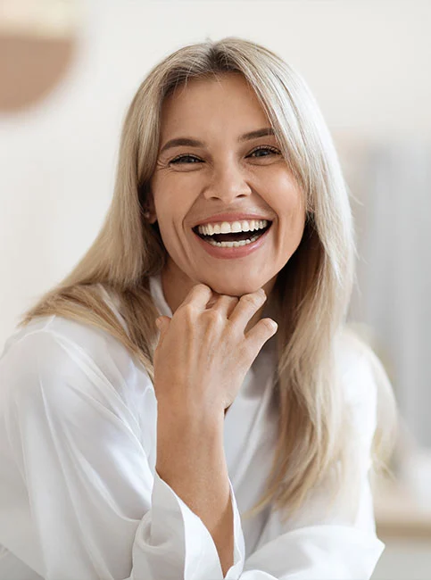 Smiling woman with hand near face in white button-up shirt