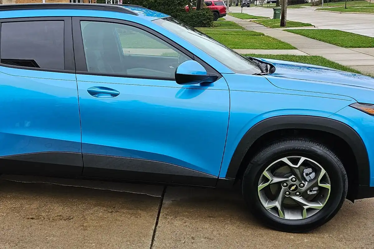 Bright blue SUV parked on suburban street with grass and homes visible