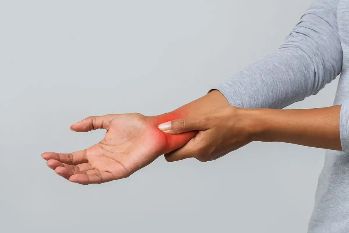 Person in gray shirt holding their wrist with red highlighted pain area