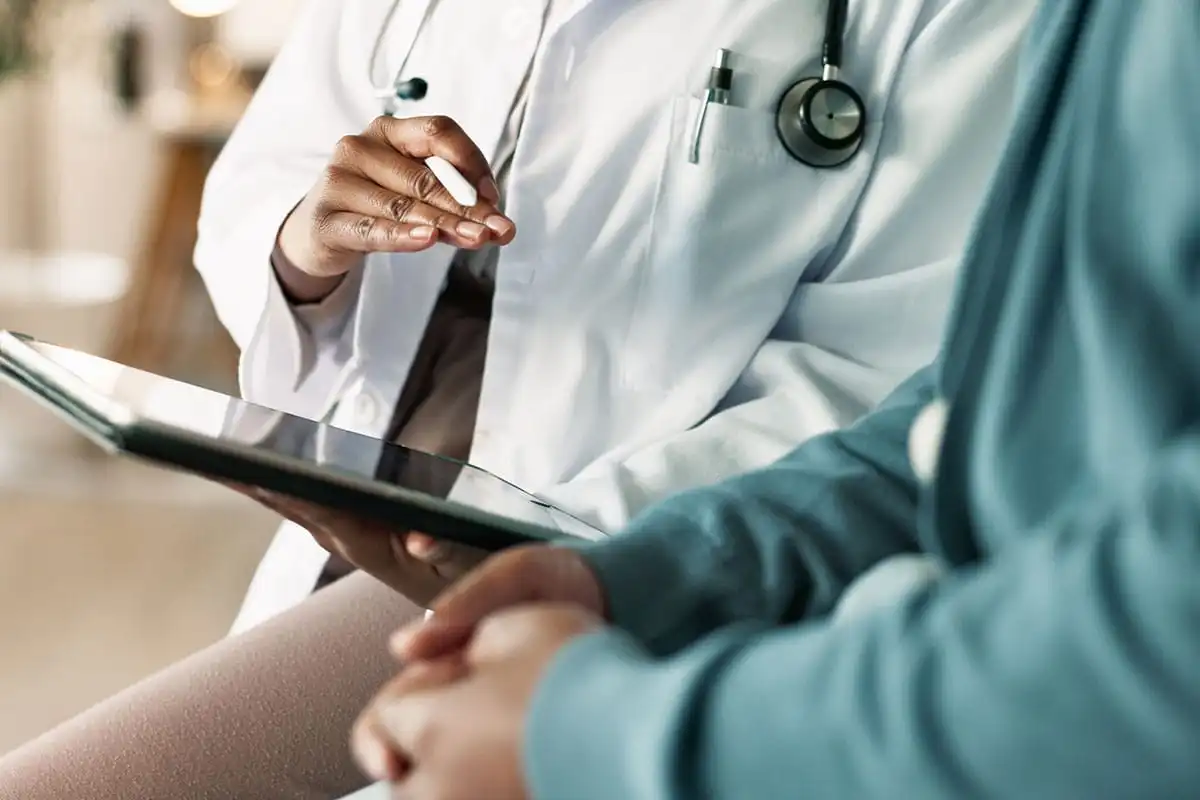 Doctor in white coat with stethoscope reviewing clipboard with patient