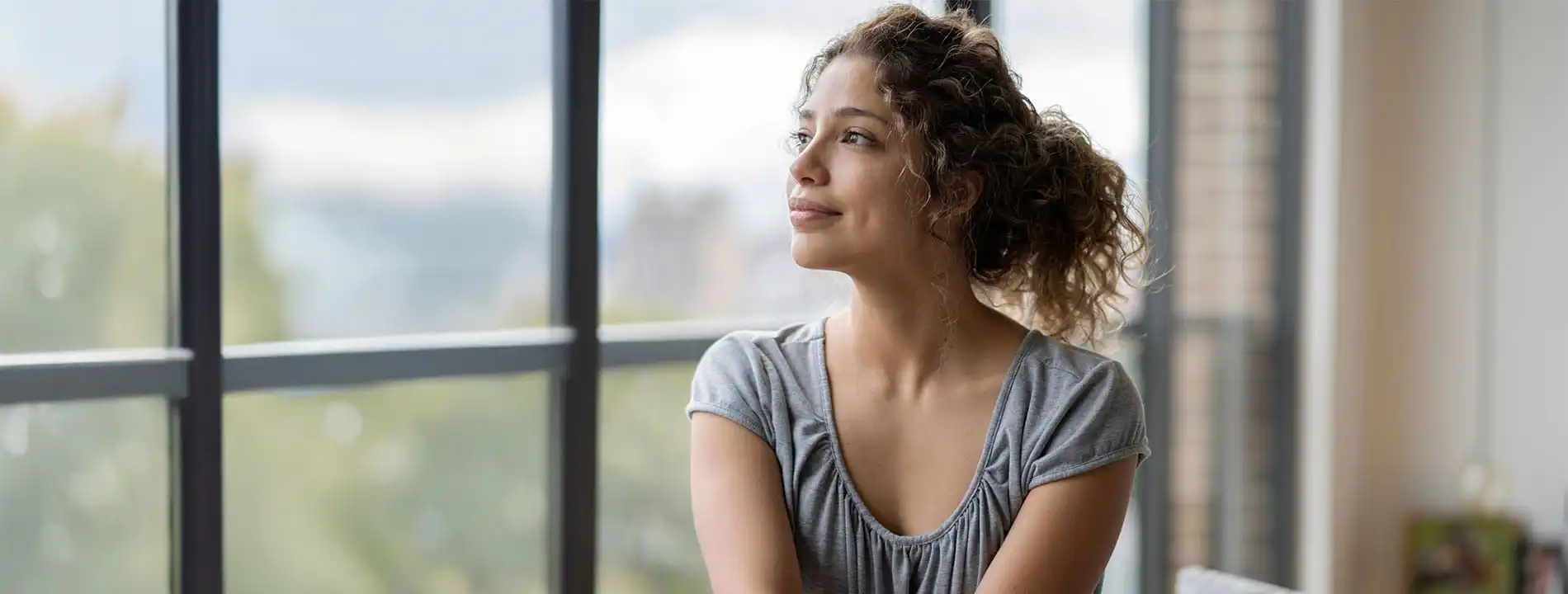 Woman looking out hospital window in contemplative pose