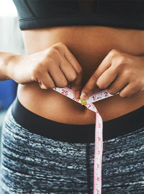 Person measuring their waist with tape measure