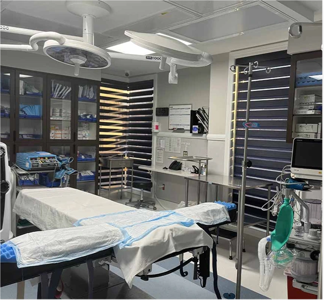 Surgical operating room with overhead lights, surgical bed, and sterilized instrument storage