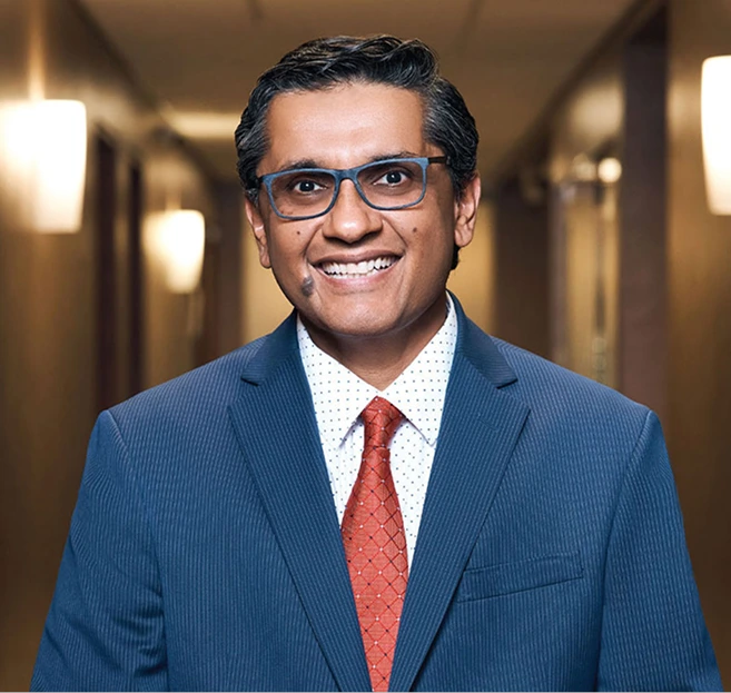 Man in blue suit and red tie smiling in professional medical office hallway