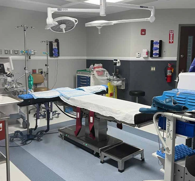 Surgical operating room with overhead lights, sterile instrument trays, and a hydraulic surgical bed