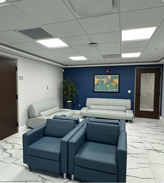 Plastic surgery practice waiting room with blue accent wall, gray seating, and modern ceiling lights