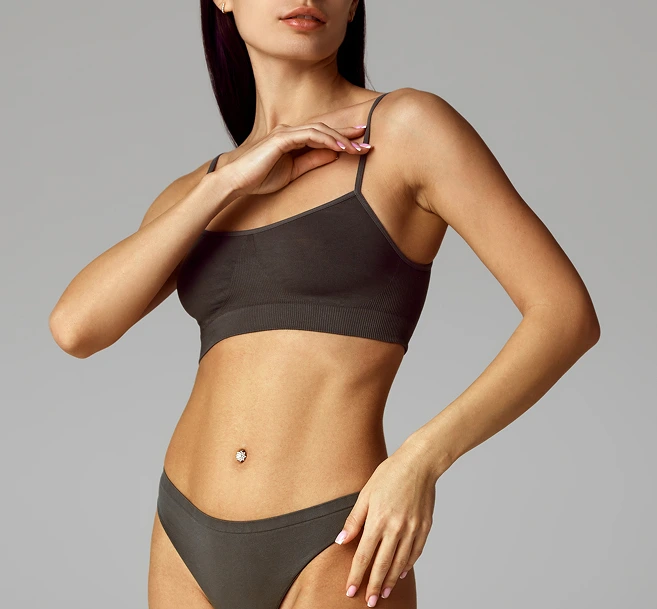 Woman in black sports bra touching her shoulder, demonstrating toned upper body