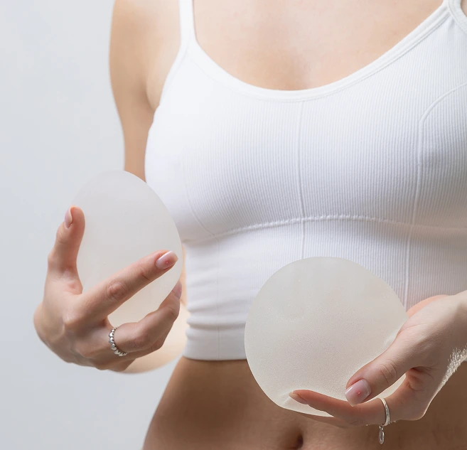 Woman holding two silicone breast implants in her hands