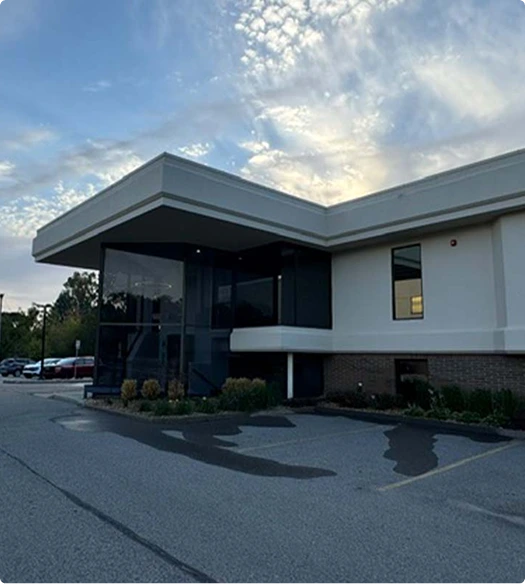 Modern white and gray surgical facility exterior with glass entrance and parking area