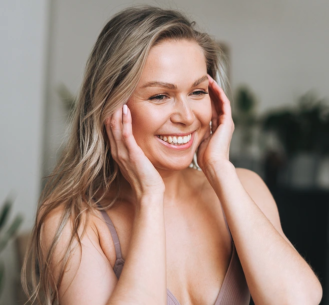 Smiling woman with hands on face, showcasing skin and natural appearance