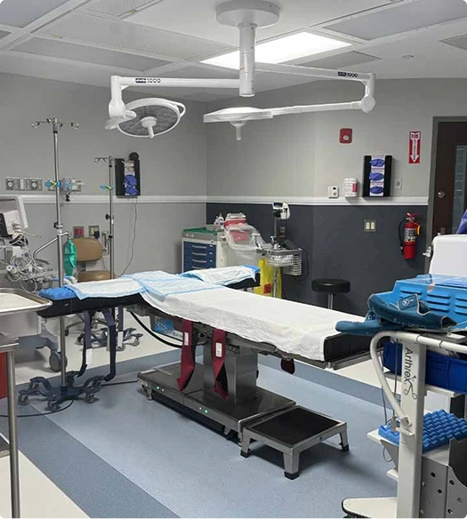 Operating room with dual overhead surgical lights, motorized surgical bed, and instrument trays