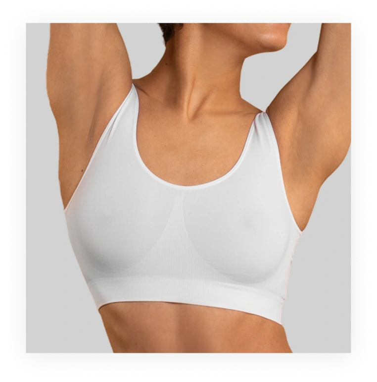 Woman from shoulders up with arms raised, showing chest and underarm area in white tank top