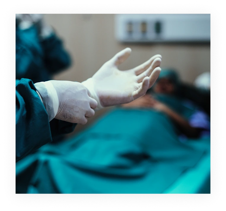 Surgeon's gloved hand positioned over patient draped in surgical blue during procedure